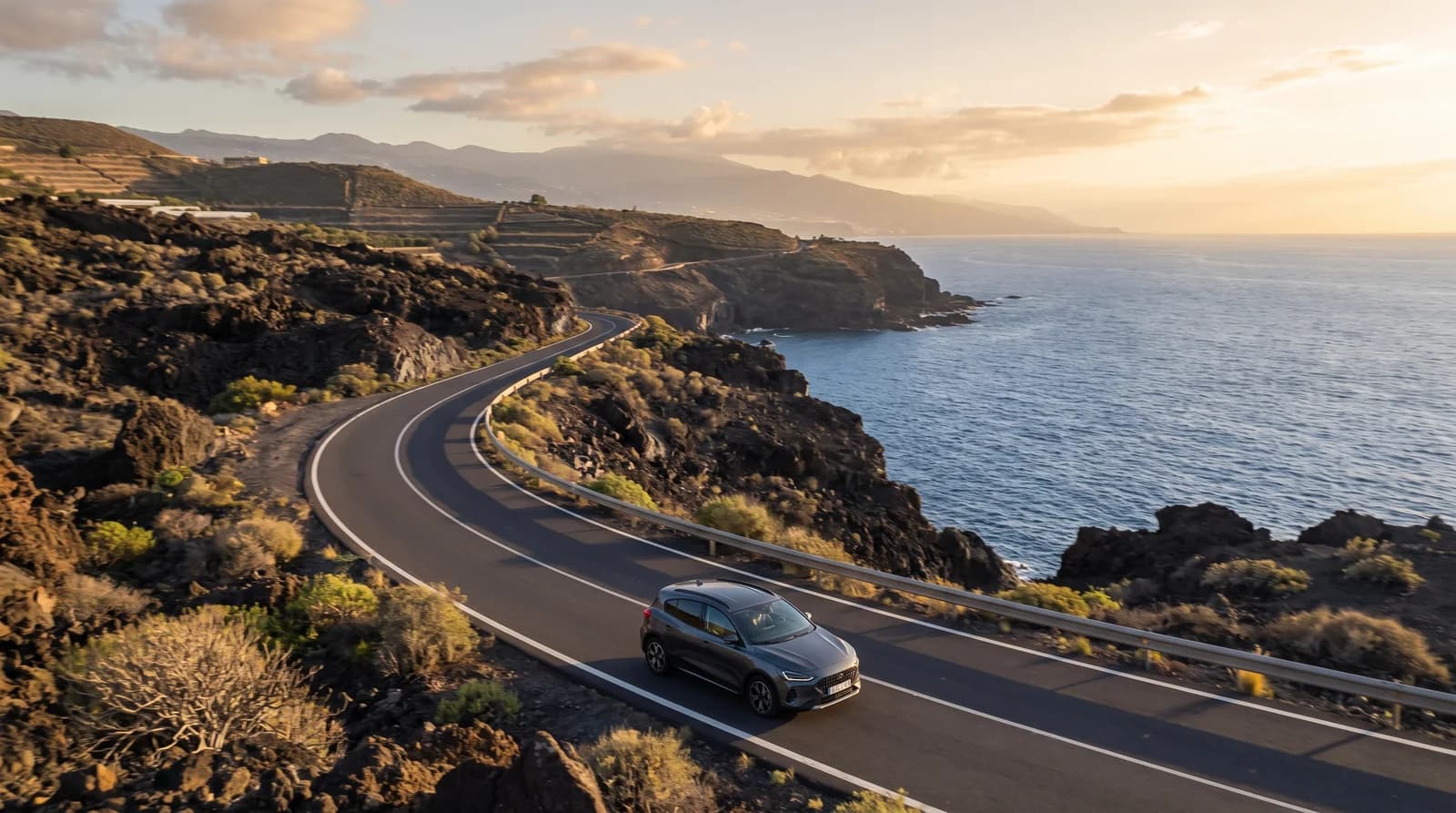 A car on a coastal road in Tenerife at sunset